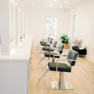 Kaemark A hair salon with white chairs and wooden floors.