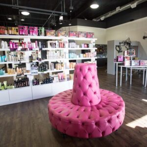 Kaemark A pink chair in a store with shelves full of hair products.