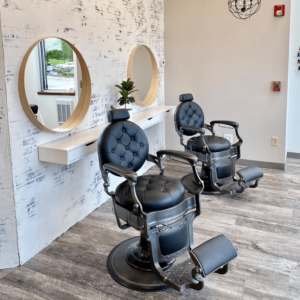 Kaemark Two barber chairs in a room with mirrors.