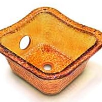 Kaemark A square glass sink with a hole in the middle.