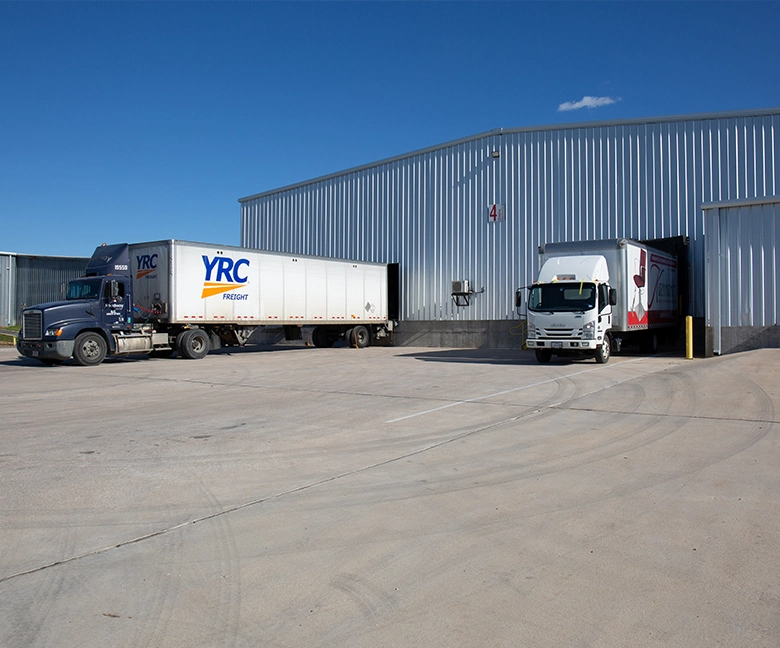 Kaemark Two trucks parked in front of a warehouse.