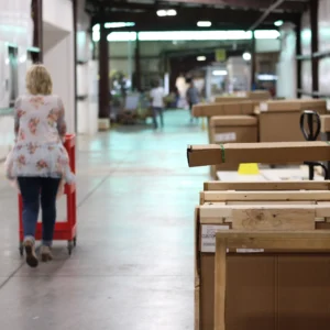 Kaemark A woman walking through a warehouse full of boxes.