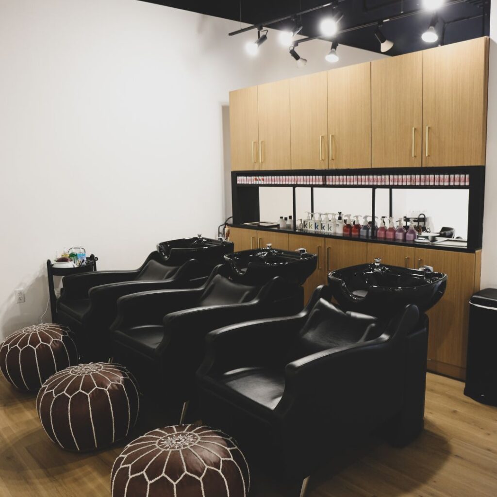 Kaemark A hair salon with black chairs and ottomans.